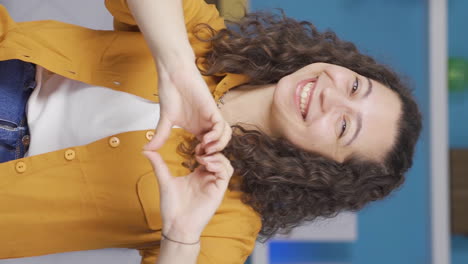 Vertical-video-of-Young-woman-making-heart-sign-at-camera.